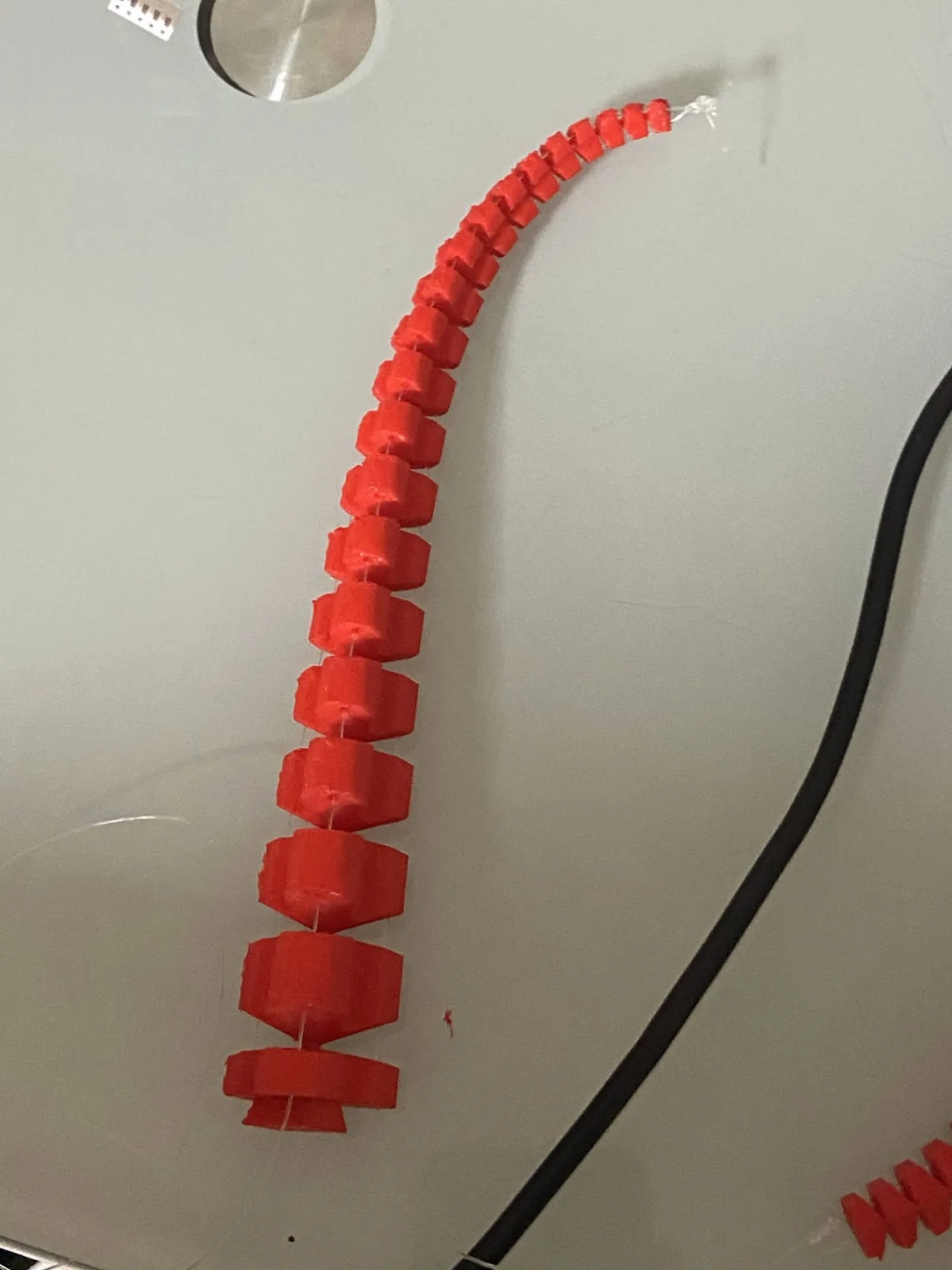 Printed two-cable SpiRob arm on a lab bench, cables routed to stepper motors